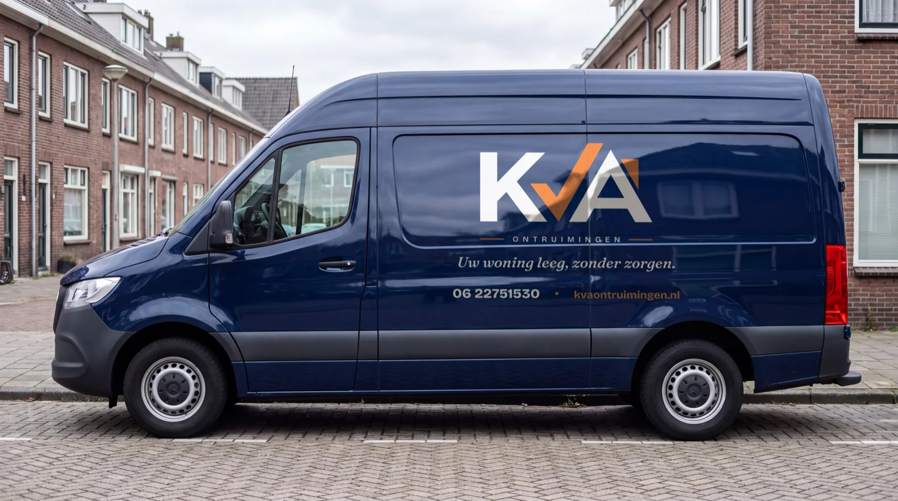 De nachtblauwe bedrijfsbus van KVA Ontruimingen met belettering: logo, de payoff en het telefoonnummer op de flank