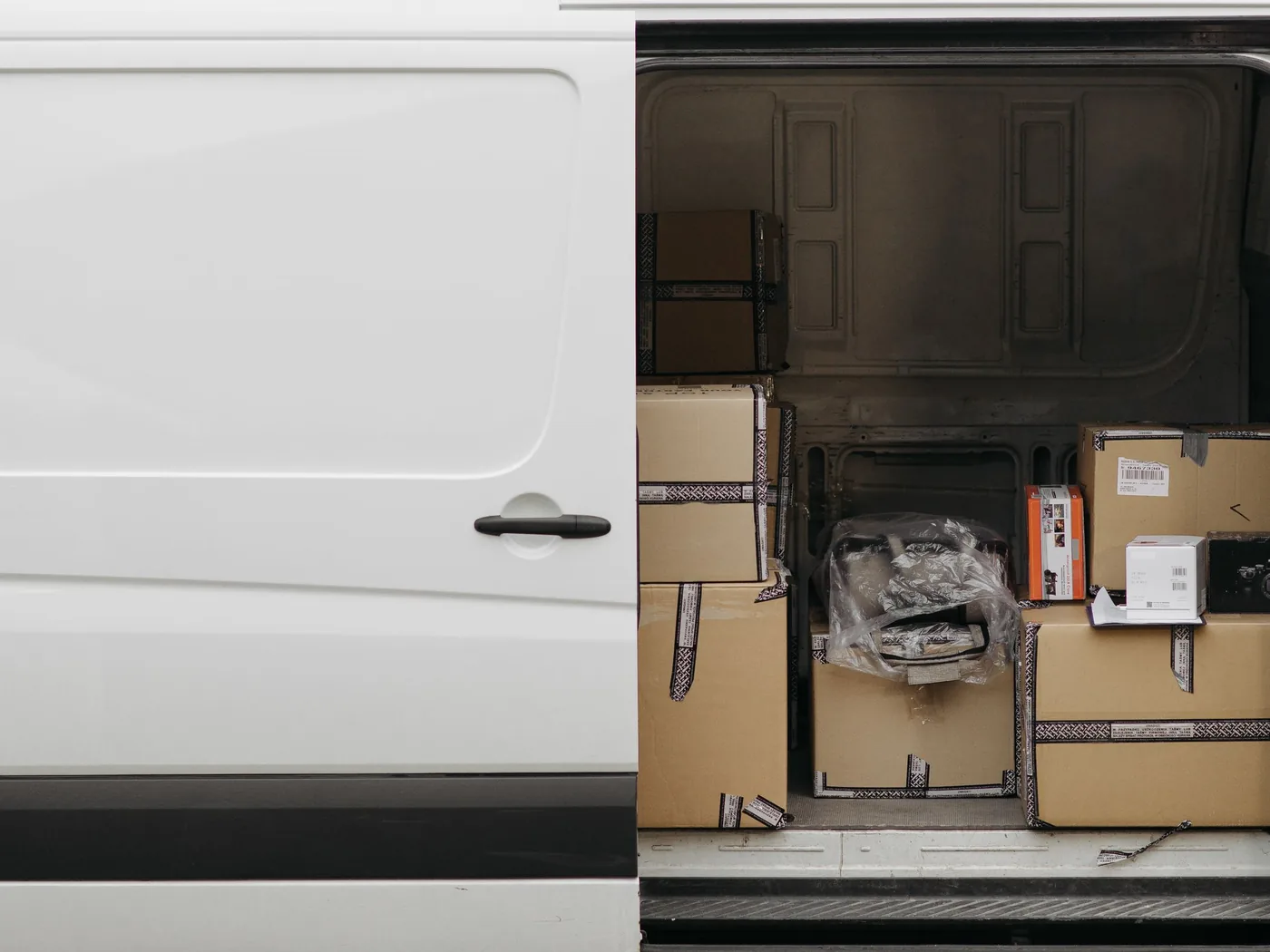 Blanco witte bestelbus met de zijdeur open en verhuisdozen klaar om afgevoerd te worden