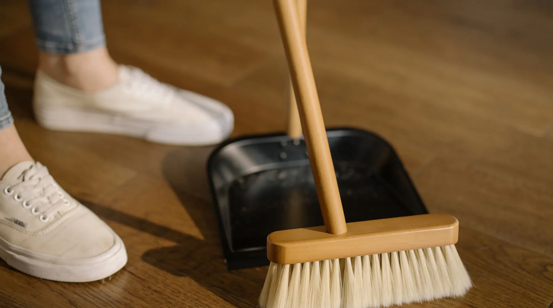 Bezem en stoffer op een geveegde houten vloer, klaar voor de sleuteloverdracht