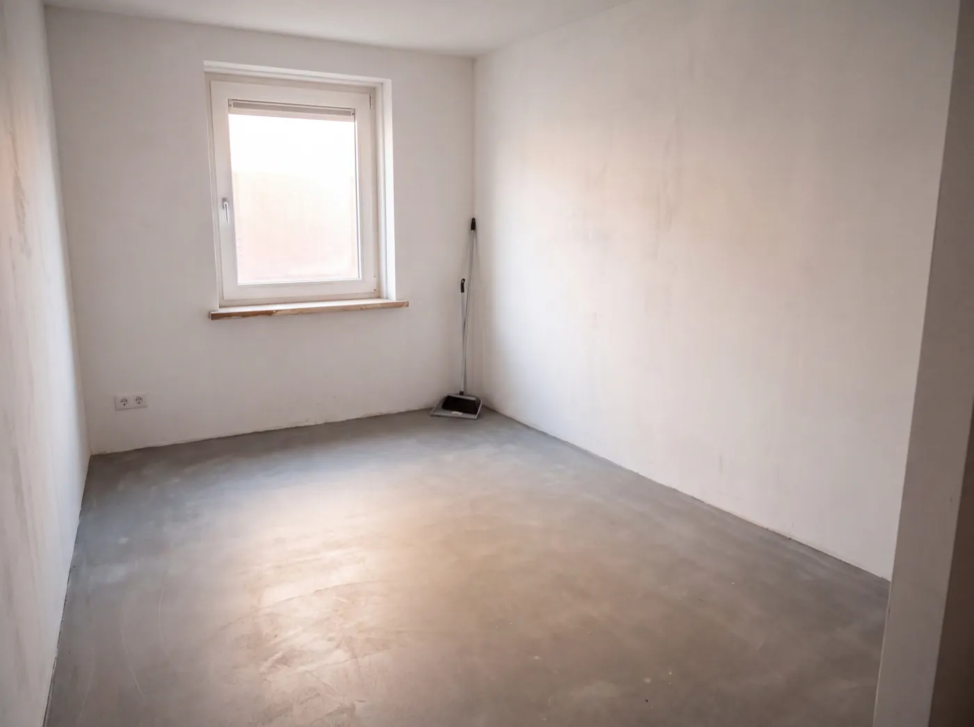 Leeggehaalde en geveegde garage met betonvloer na een garageontruiming